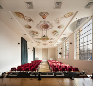 sala-conferenze-poltrone-rosse-soffitto-con-panelli-decorati-disegni-di-haeckel-meduse