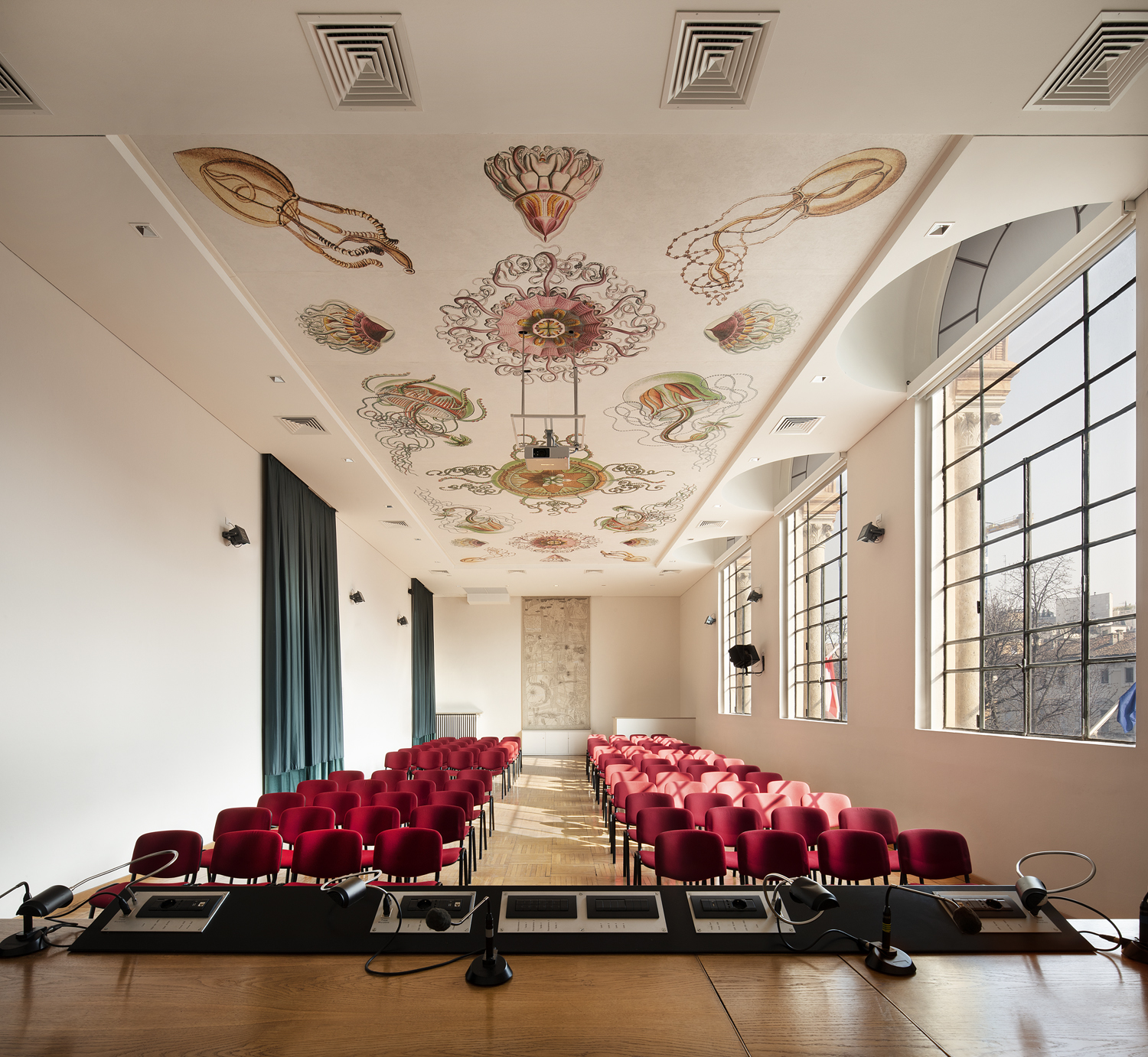 sala-conferenze-poltrone-rosse-soffitto-con-panelli-decorati-disegni-di-haeckel-meduse